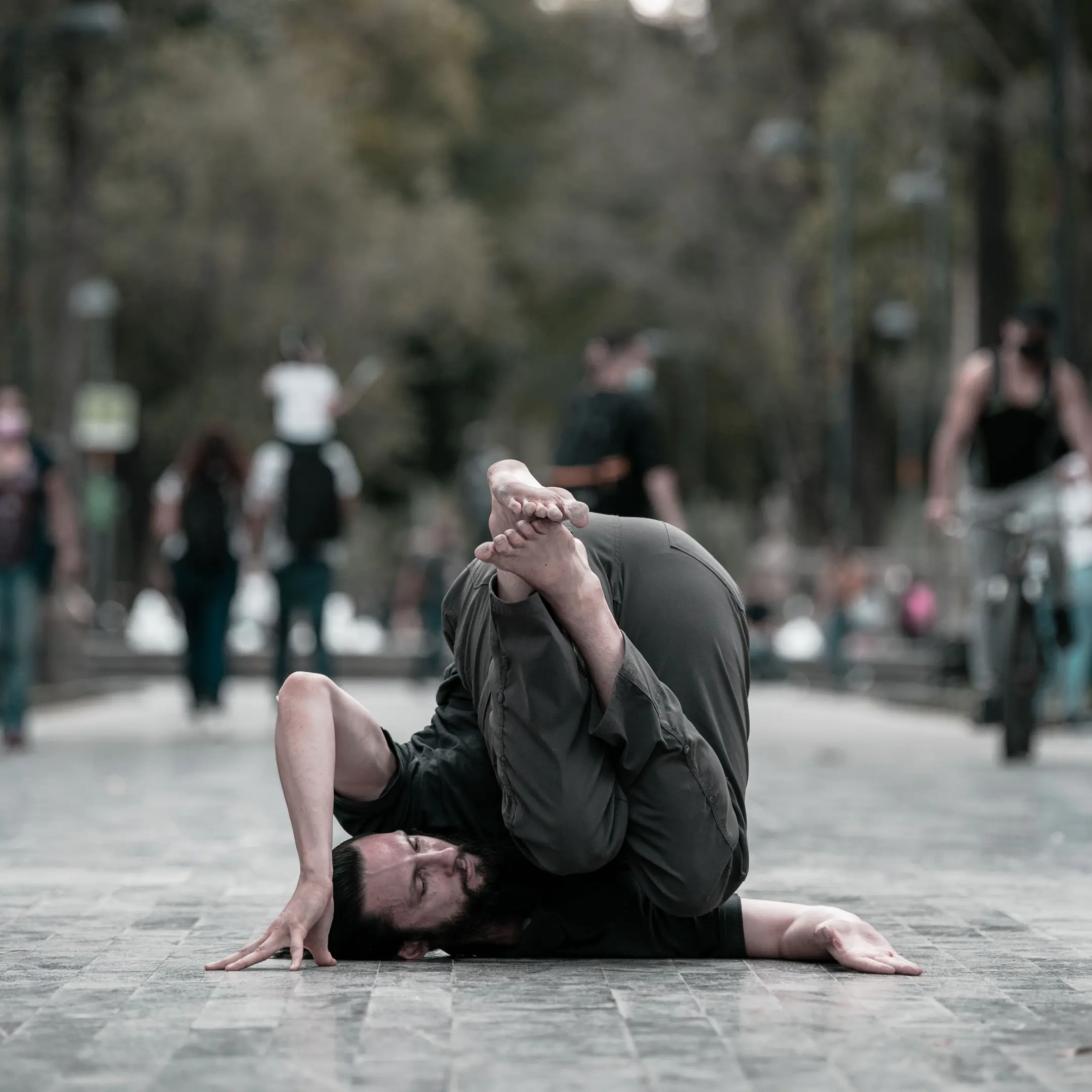 Samuel Hobbs performing a compact shoulder stall in the middle of a Mexico City park sidewalk.